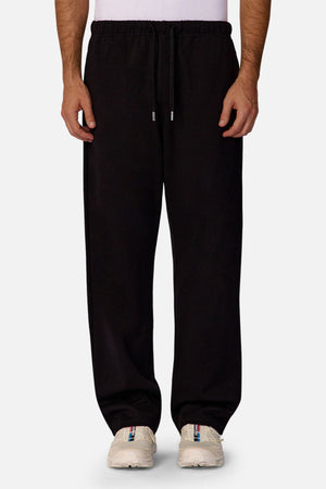 Dressed in Industrie The Astoria Lux Tech Trackpant and white sneakers, this waist-down shot against a light background captures casual style paired with premium comfort.