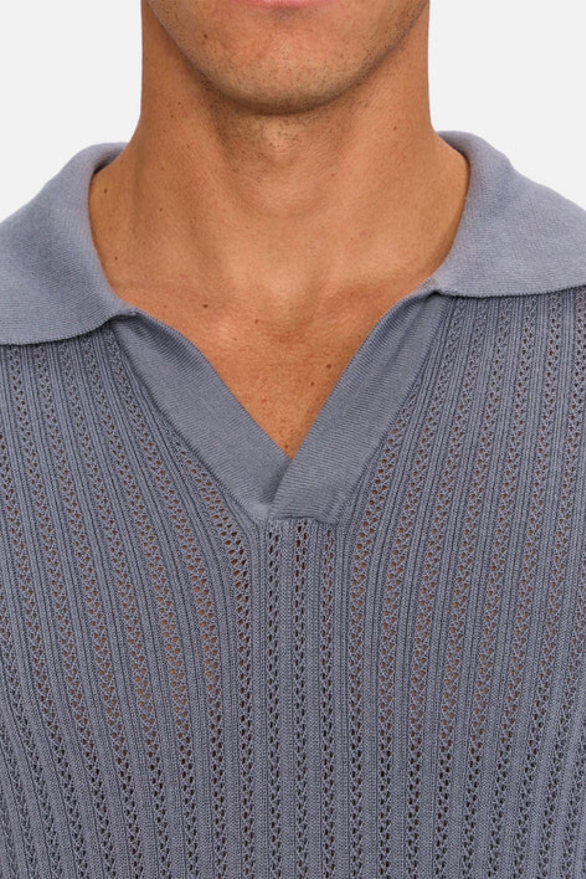A close-up of a person wearing the Industrie The Bellano Polo, a men's 100% cotton knit shirt in light blue with a textured vertical ribbed pattern, collared V-neck opening, and visible neck and upper chest.