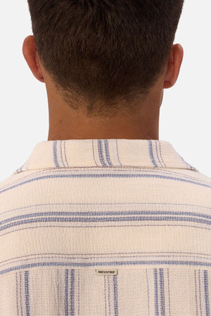 A person is seen from behind wearing the Industrie The Bowment Short Sleeve Shirt in cream with blue textured stripes, collar detail, and a visible "INDUSTRIE" tag—an ideal choice for any casual wardrobe.
