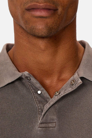 A close-up shows a man's lower face and neck wearing Industrie The Burbank Polo Track in faded gray with the top buttons undone. Made from quality materials, this versatile polo stands out against a plain, light background.