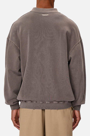 A person is seen from behind wearing the Industrie The Burbank Polo Track, a loose-fitting, faded gray premium sweatshirt with dropped shoulders, subtle neckline text, and beige pants set against a plain light background.