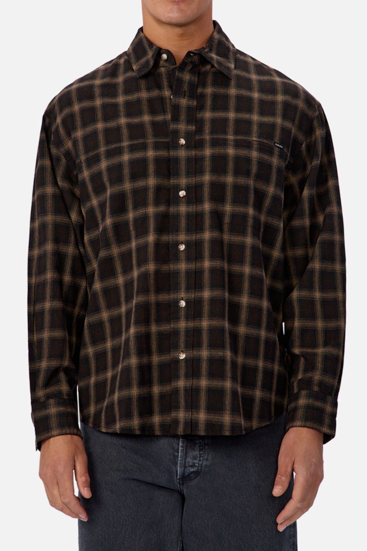 A person wearing the Industrie The Carrington Shirt, a regular fit long-sleeve shirt with a brown and black plaid pattern, paired with dark jeans and standing against a plain light background.