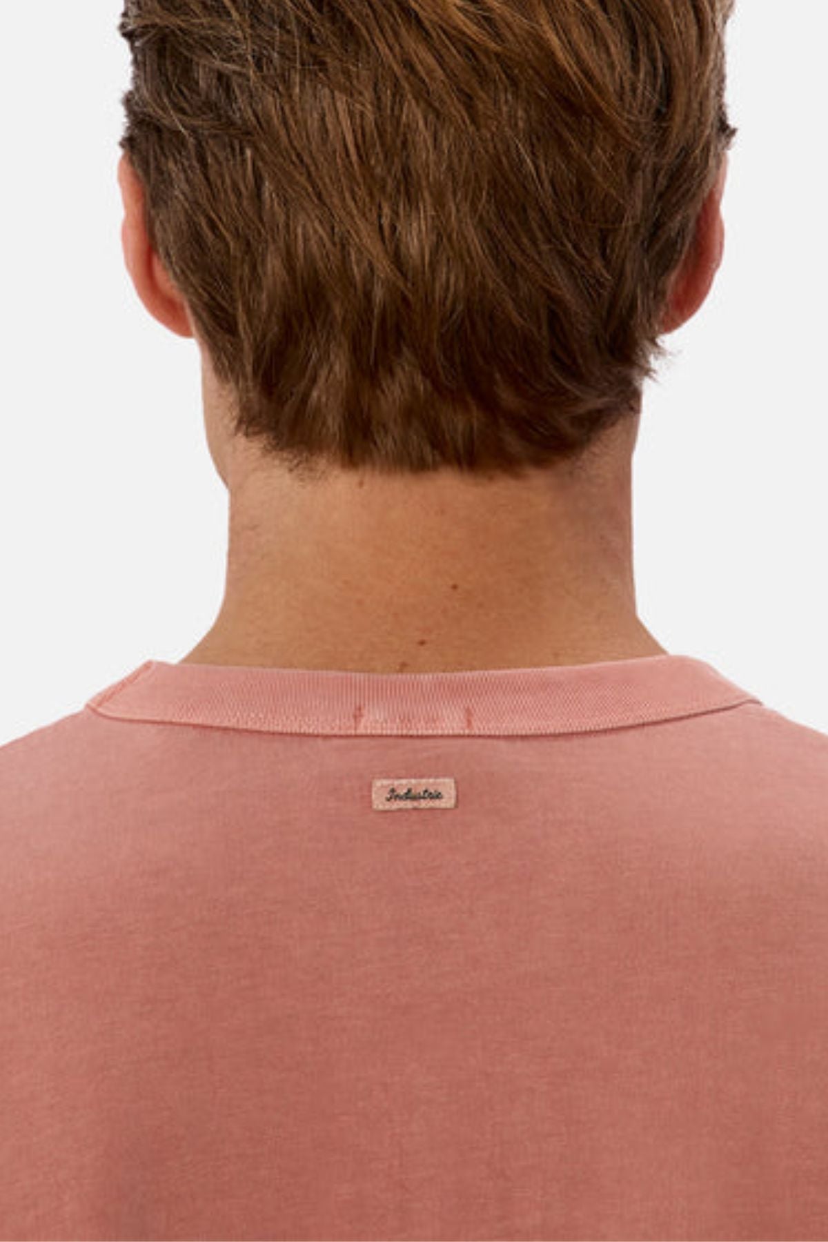 A person with short brown hair is shown from the back, wearing a pink Industrie The Del Sur Tee crafted from heavyweight fabric, featuring a small "Jack & Jones" label at the neckline. The oversized fit adds a modern touch against the plain white background.