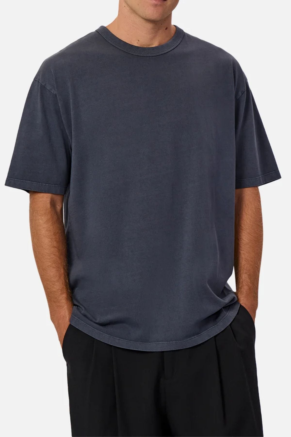 A person wears Industrie The Del Sur Tee, a loose-fit, heavyweight short-sleeve dark gray T-shirt, and black pants with hands in pockets, shown from shoulders to thighs against a plain background.