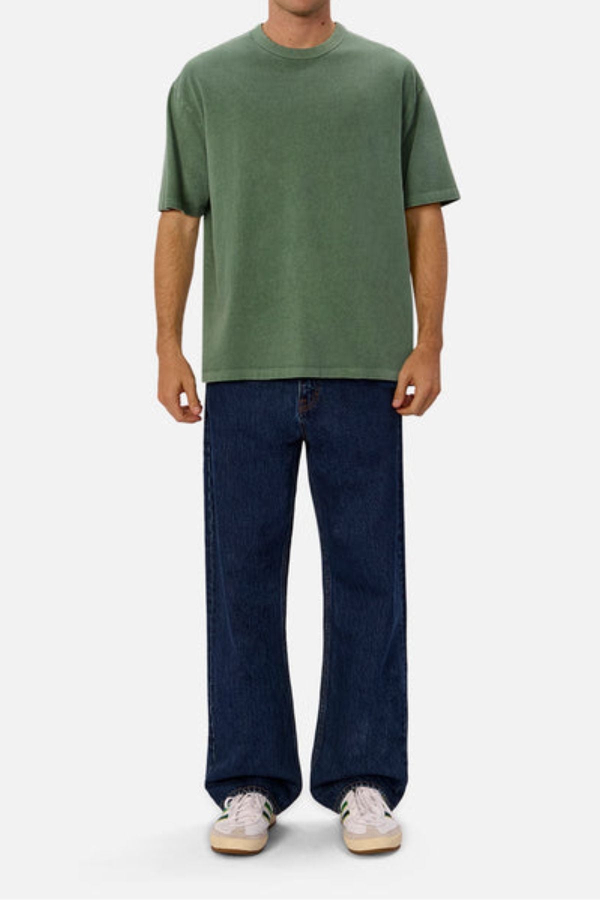 Wearing an oversized fit of the Industrie The Del Sur Tee in green, paired with dark blue wide-leg jeans and white sneakers, a person stands against a plain white background. The emphasis is on the relaxed, stylish look highlighted by the shirt's heavyweight fabric.