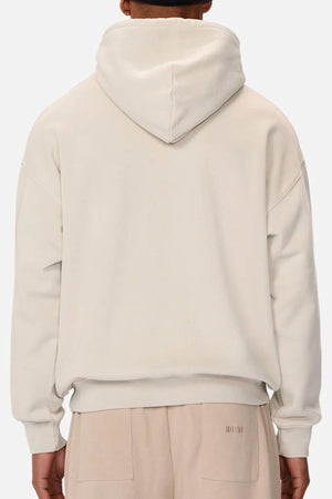 A person is shown from the back wearing the Industrie The Del Sur Washed Hoodie in light beige with matching sweatpants. The hood is up, highlighting the oversized fit as their arms rest by their sides.
