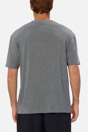 A person with light brown hair is seen from behind, wearing the Industrie The Freeman Athletic Tee in plain grey and dark shorts, standing against a plain light background.