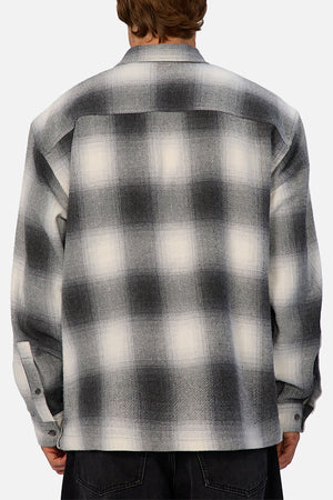 A person is shown from behind wearing the Industrie The Highland Shirt in black, white, and gray with long sleeves, dark pants, a relaxed fit, and a subtle shadow check pattern for effortless style.