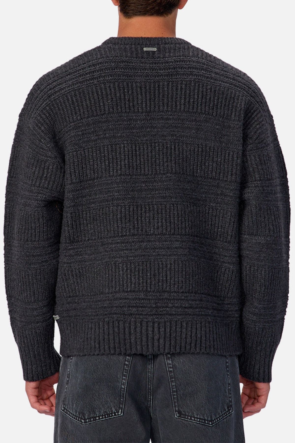 A person is shown from the back wearing the Industrie The Huntington Knit, a regular fit dark gray crew neck sweater with a textured horizontal ribbed pattern, paired with faded black jeans.