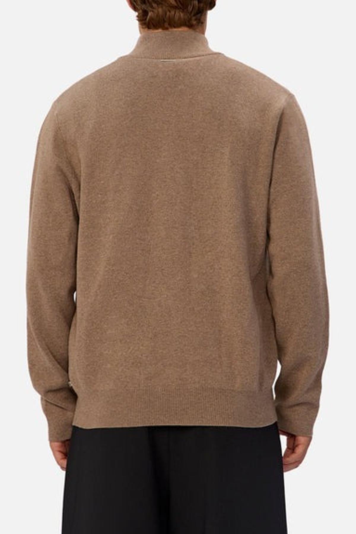 A person is shown from the back wearing the Industrie The Lakewood Zip Neck Knit in light brown cotton with rib knit cuffs and black pants, standing against a plain light background.