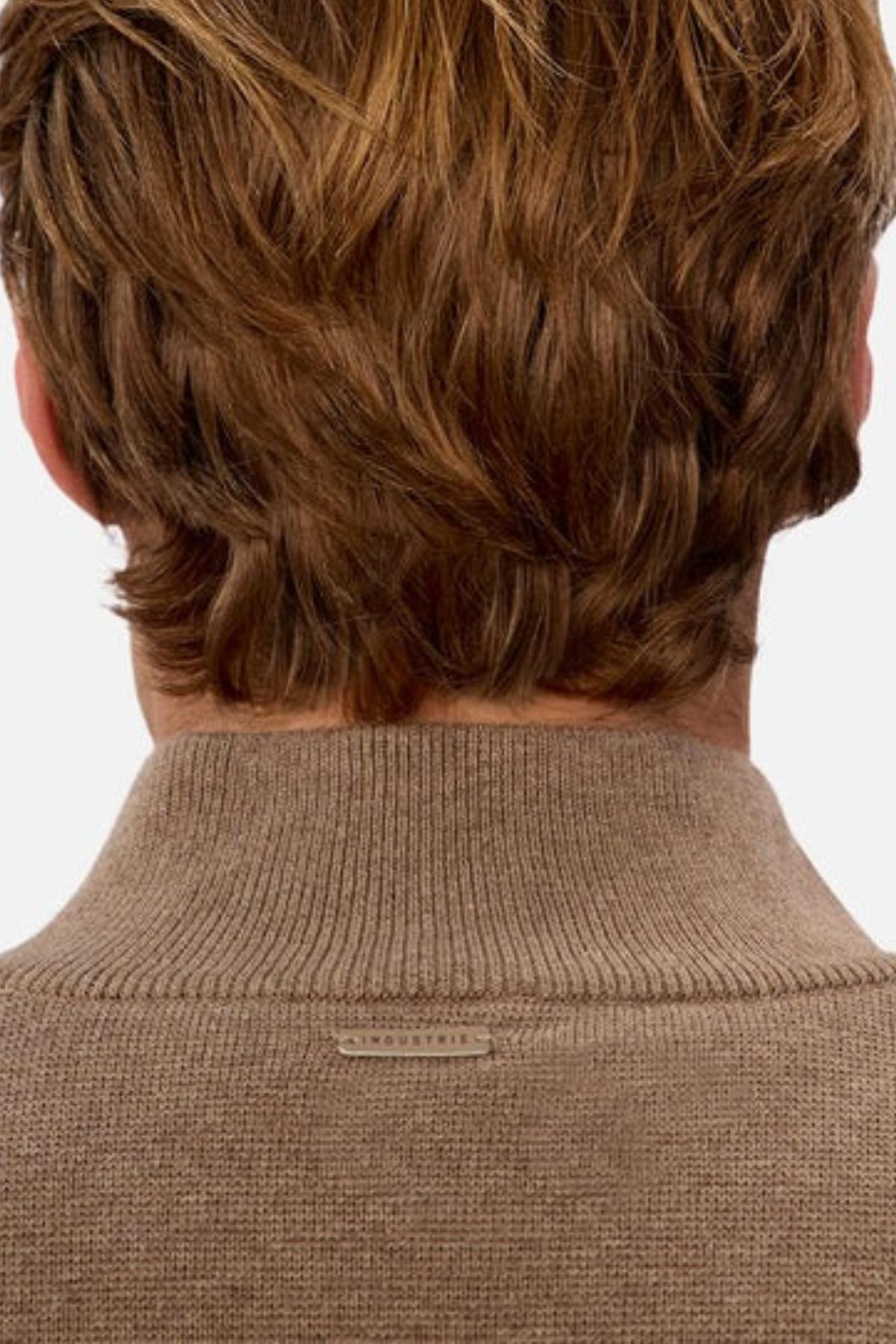 A close-up of the back of a person’s head and neck, showing light brown hair and wearing the Industrie The Lakewood Zip Neck Knit in beige with rib knit cuffs and a small metallic brand tag on the collar.