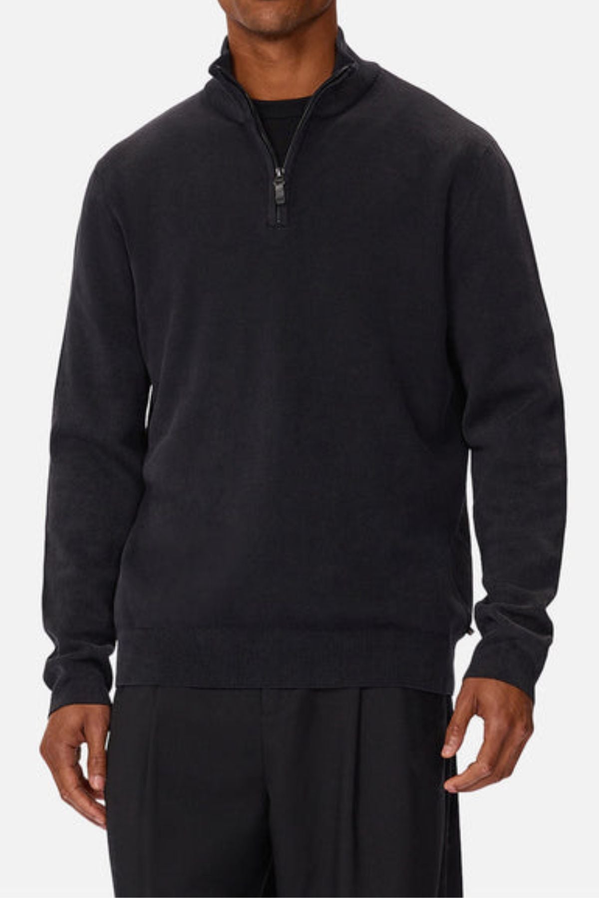 A man wearing the Industrie The Lakewood Zip Neck, a black regular fit cotton jumper, over a black shirt and pants, stands against a plain white background.