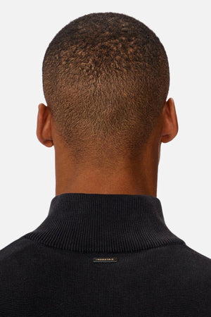 A person with short hair is seen from behind, wearing the Industrie The Lakewood Zip Neck jumper in black regular fit cotton, featuring a subtle ribbed texture and a small metallic tag near the neckline.