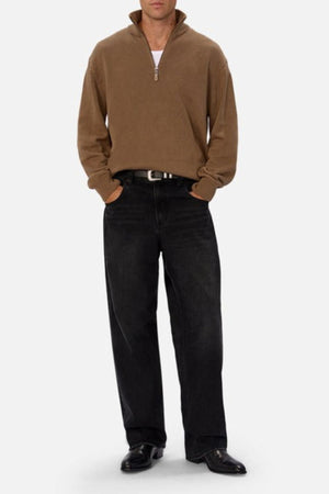 Wearing the Industrie The Maine Zip Neck Knit in regular fit over a white shirt, paired with black jeans and black shoes, a person stands hands-in-pockets against a light background.