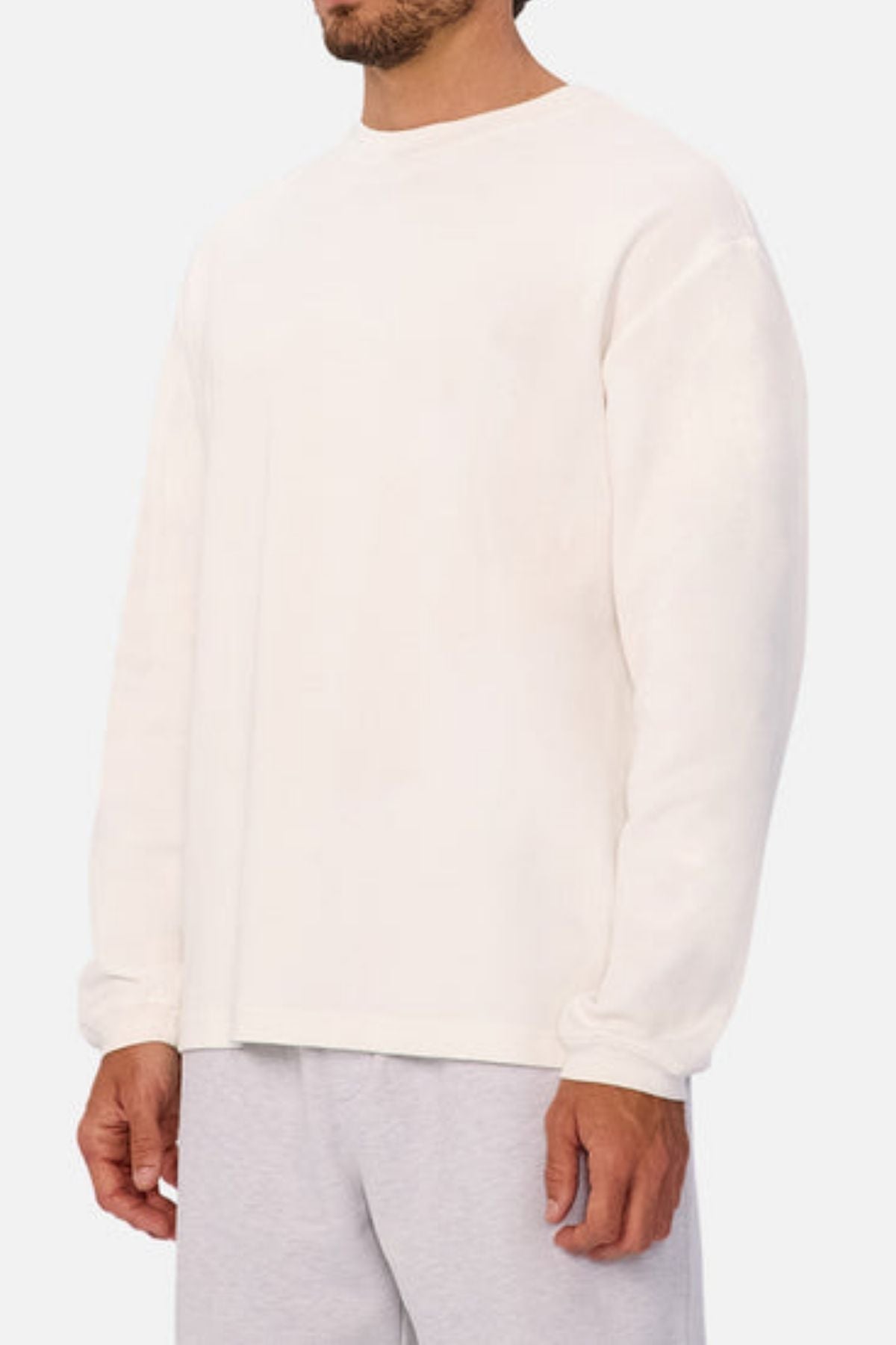 A man wears the Industrie The Marlon Long Sleeve Tee, made from 100% cotton with a textured finish, paired with light grey shorts. He is shown from shoulders to mid-thigh, standing against a light grey background.