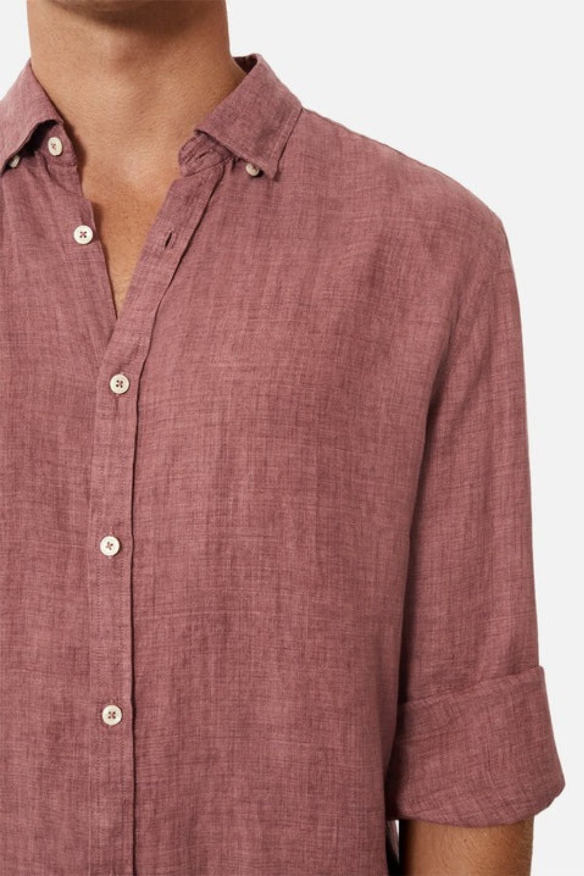 A person sporting *Industrie The Midland Shirt* in a relaxed fit, displaying the INDUSTRIE logo. This long-sleeved, button-up shirt is presented in a dusty rose shade with rolled-up sleeves and the top button left undone, all crafted from a fabric with a textured linen-like feel.