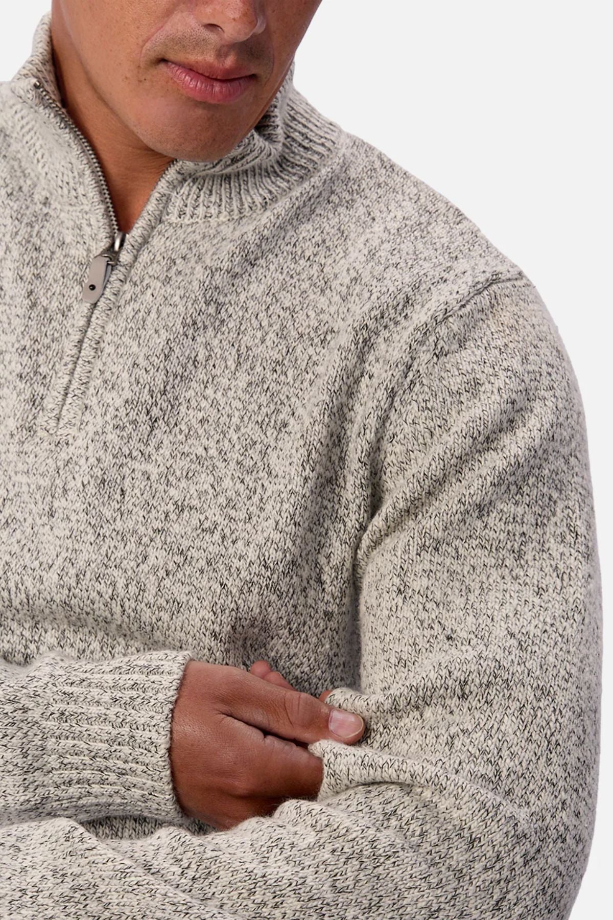 A person wears the Industrie The Montauk Knit zip-up sweater in light gray with a subtle marled design, touching the sleeve. Their face is partly visible against a white background.