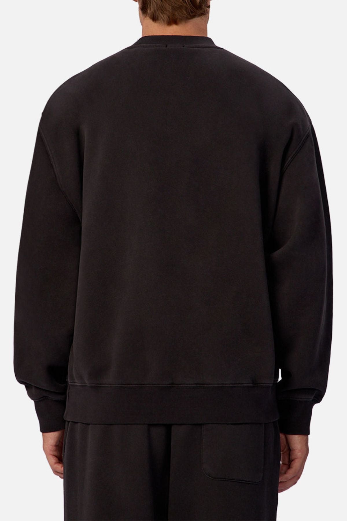 A person is seen from behind in a loose, oversized black Industrie The New Del Sur Sweatshirt and matching pants with subtle branding, set against a light gray background.