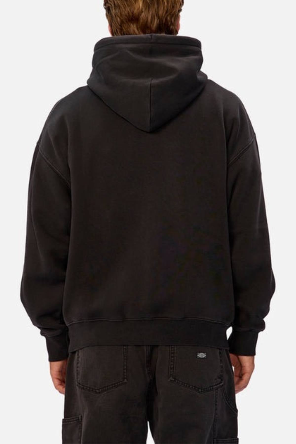 A person with short light brown hair is seen from behind wearing an oversized Industrie The New Del Sur Washed Hoodie and black jeans, standing against a plain light background.