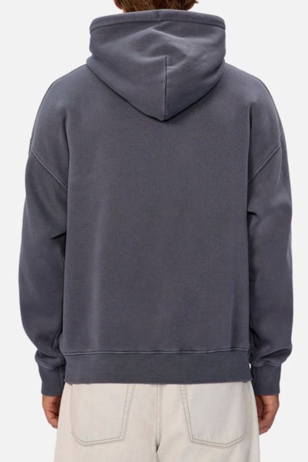 A person is seen from behind wearing the Industrie The New Del Sur Washed Hoodie in dark gray with an oversized fit and off-white pants, hood up, set against a plain light-colored background.