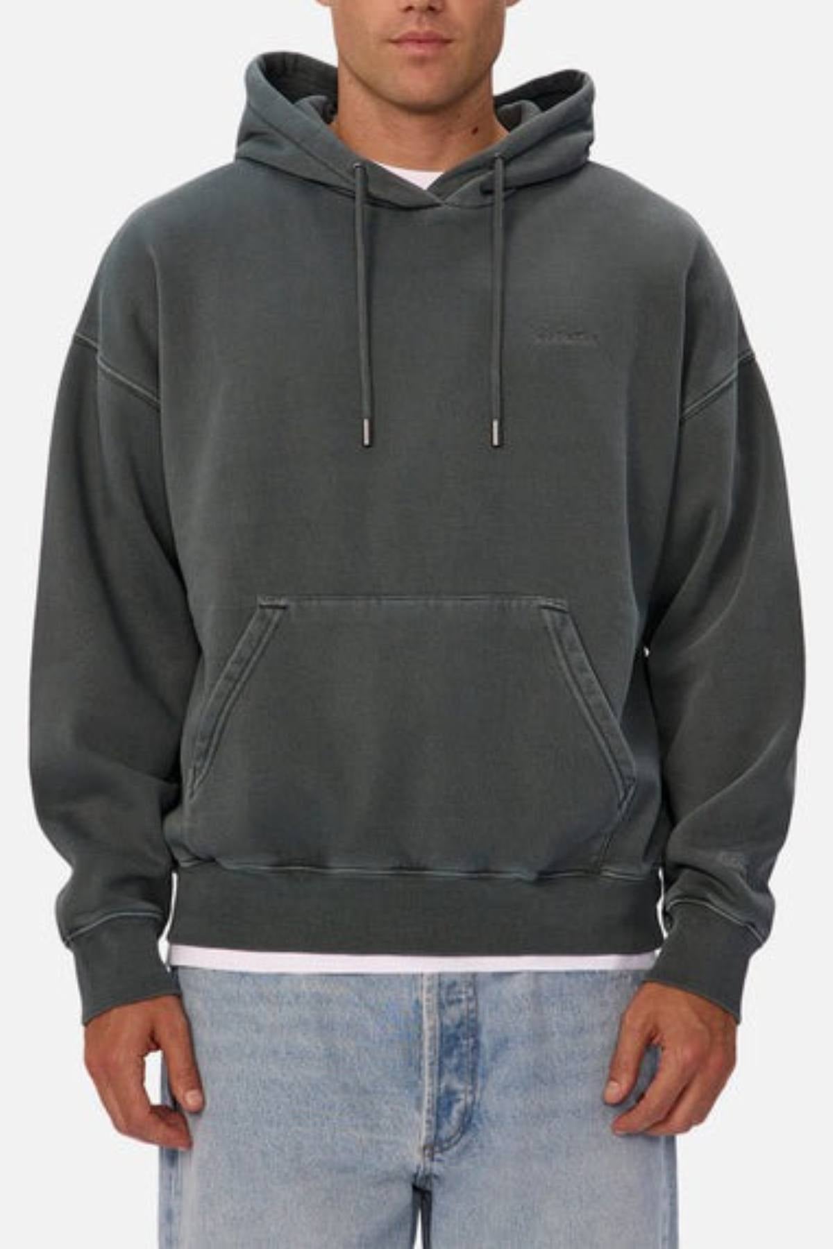 A person wears the Industrie The New Del Sur Washed Hoodie in dark gray, featuring an oversized fit and front pocket, styled with light blue jeans, shown from the waist up against a plain background.