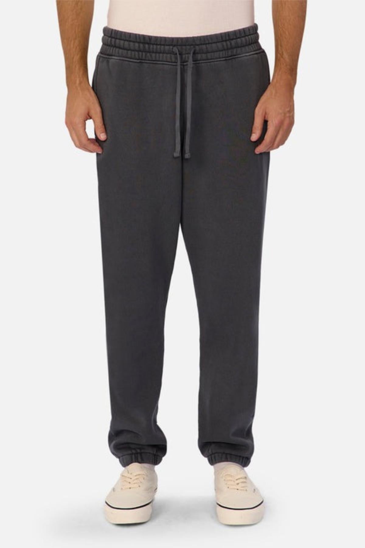 Someone wears the Industrie The New Del Sur Washed Trackpant in dark gray, featuring a drawstring and elastic waist. Paired with a light shirt and white sneakers, it creates an easy, oversized-fit look with hands in pockets.