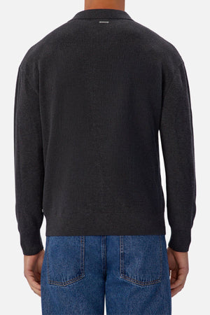 A person wearing the Industrie The New England Polo Knit in a dark color and blue jeans, shown from the back against a plain light background.
