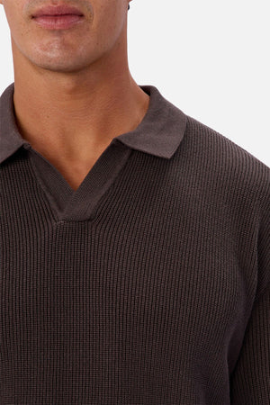 A person wears the Industrie The New England Polo Knit, a ribbed dark brown 100% cotton sweater with a collared V-neck. Only their lower face and upper chest appear against a plain white background.