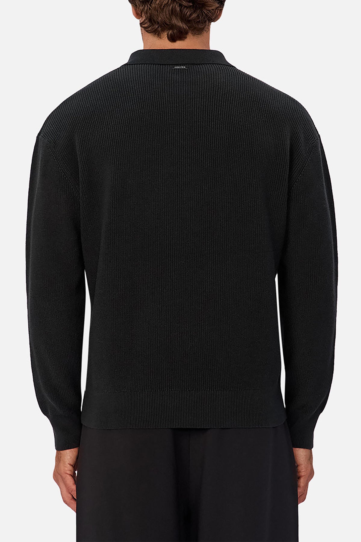 A person viewed from behind wears the Industrie The New England Polo Knit, a black long-sleeve knit sweater, styled with loose black pants against a simple light gray background.