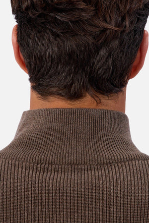 The image shows the back of a person with short, dark hair wearing the Industrie The New England Zip Neck Knit, a ribbed brown men’s cotton sweater. The background is plain and light-colored.