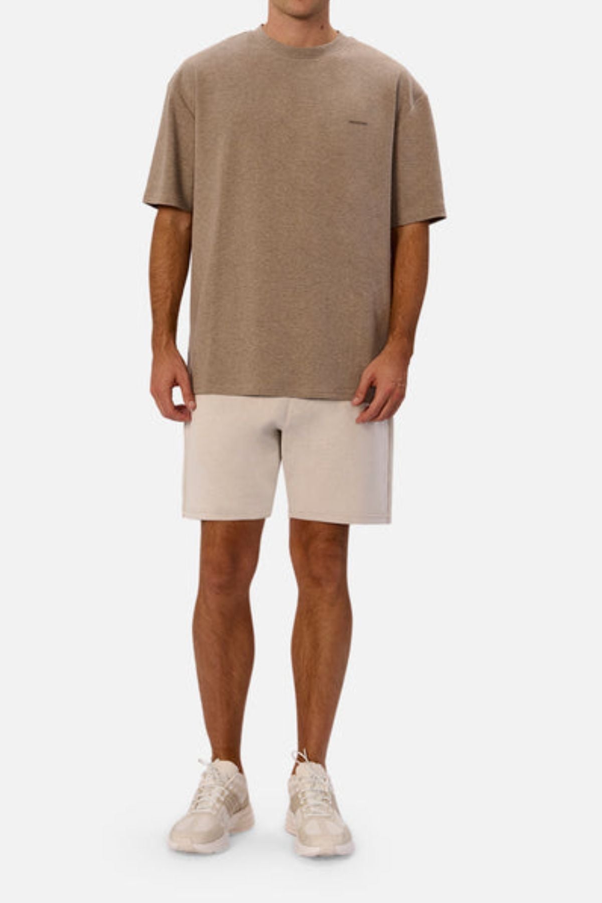 Wearing Industrie The Newport Tee in an oversized fit, paired with light-colored shorts and white sneakers, the individual stands against a plain background. Made from 100% cotton, the ensemble exudes a casual and relaxed vibe.