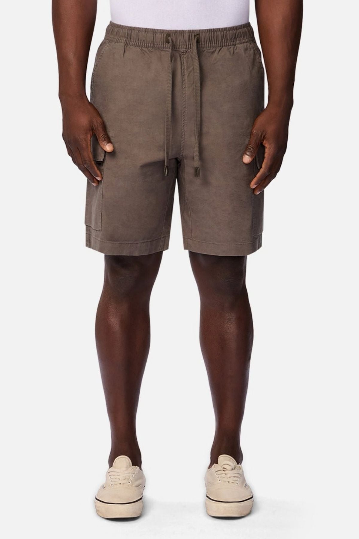 A person wearing an Industrie white shirt, Industrie The Platoon Combat Short in taupe with an elastic waistband, and beige sneakers stands against a plain white background.