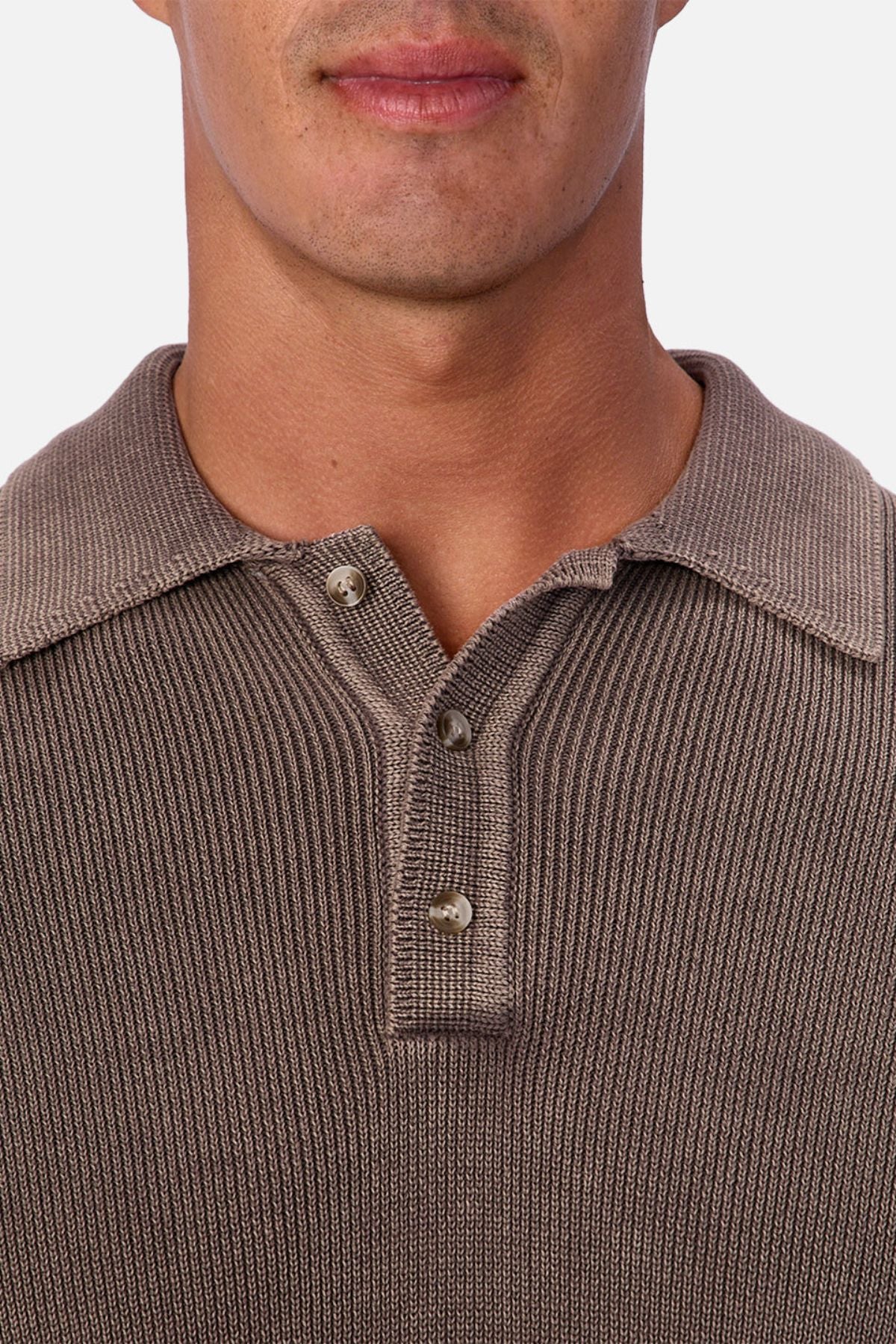 A close-up shows a person wearing the Industrie The Sawtelle Knit—a ribbed brown 100% cotton shirt with a classic collar and three buttons, two fastened. Only the lower part of their face is visible from the nose down.