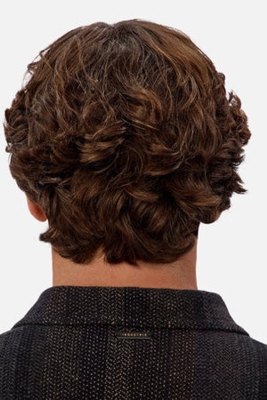 The image shows the back view of a person with thick, wavy brown hair wearing the Industrie The Sonoran Long Sleeve Shirt in a dark textured fabric, highlighting the shirt’s stylish look and their hairstyle against a light gray background.