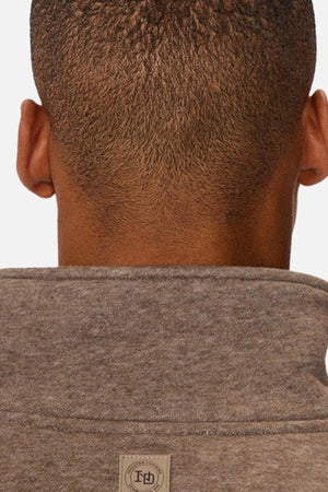 A close-up shows the back of a person's head with short, textured hair, wearing the Industrie The Staunton Tracktop in heather gray, featuring branded trims and a small rectangular tag near the collar.