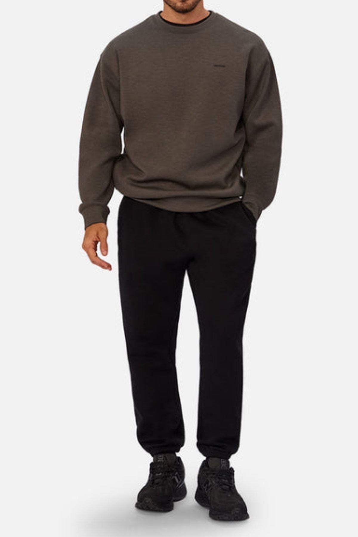 A man models the Industrie The Tech Del Sur Sweat in dark olive green, paired with black jogger pants and black sneakers, standing against a plain white background with his face not shown.