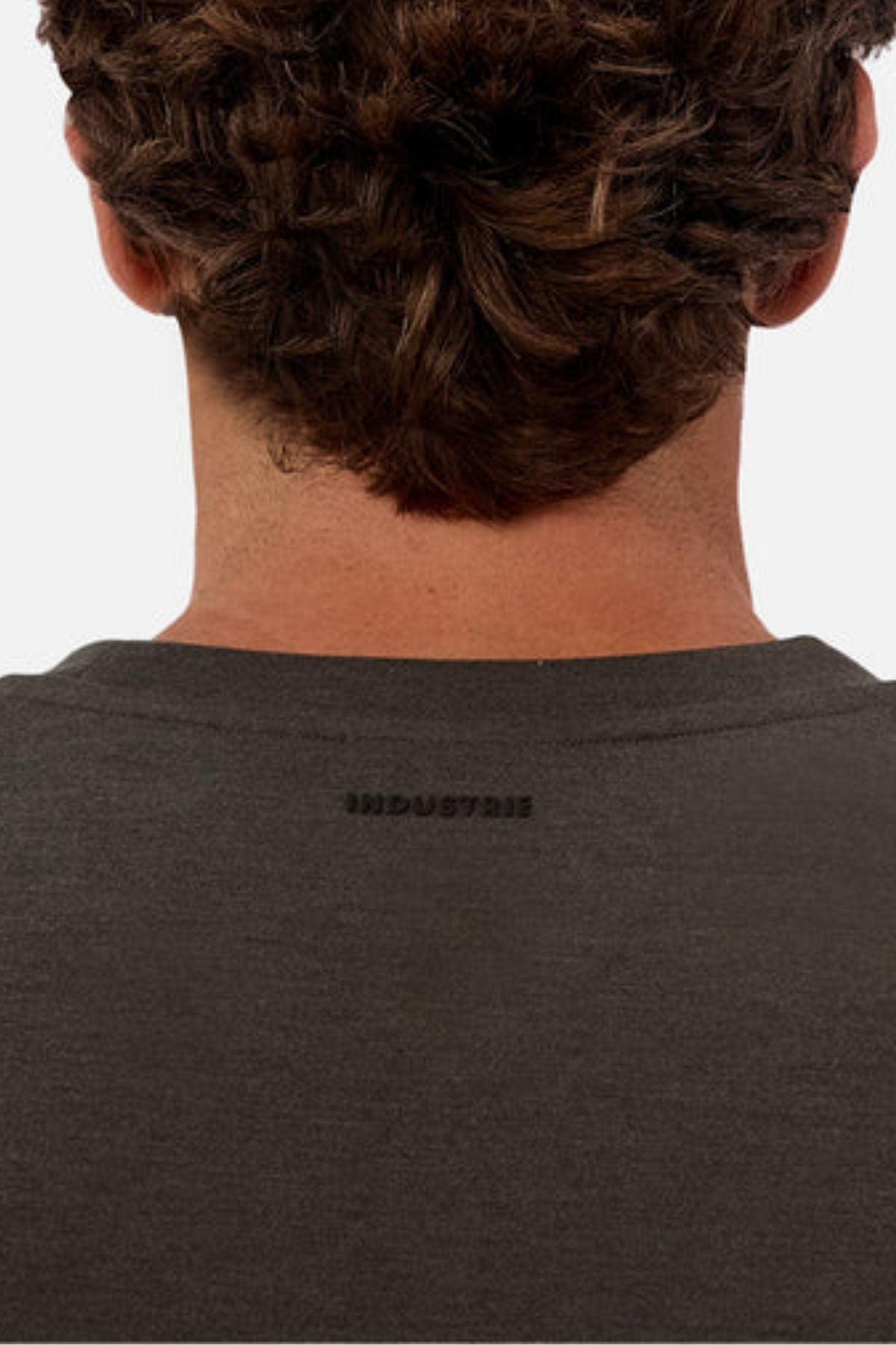 The back view of a person with curly brown hair wearing the Industrie The Tech Del Sur Sweat in dark grey. "INDUSTRIE" is printed in small black letters on the upper back of the shirt.