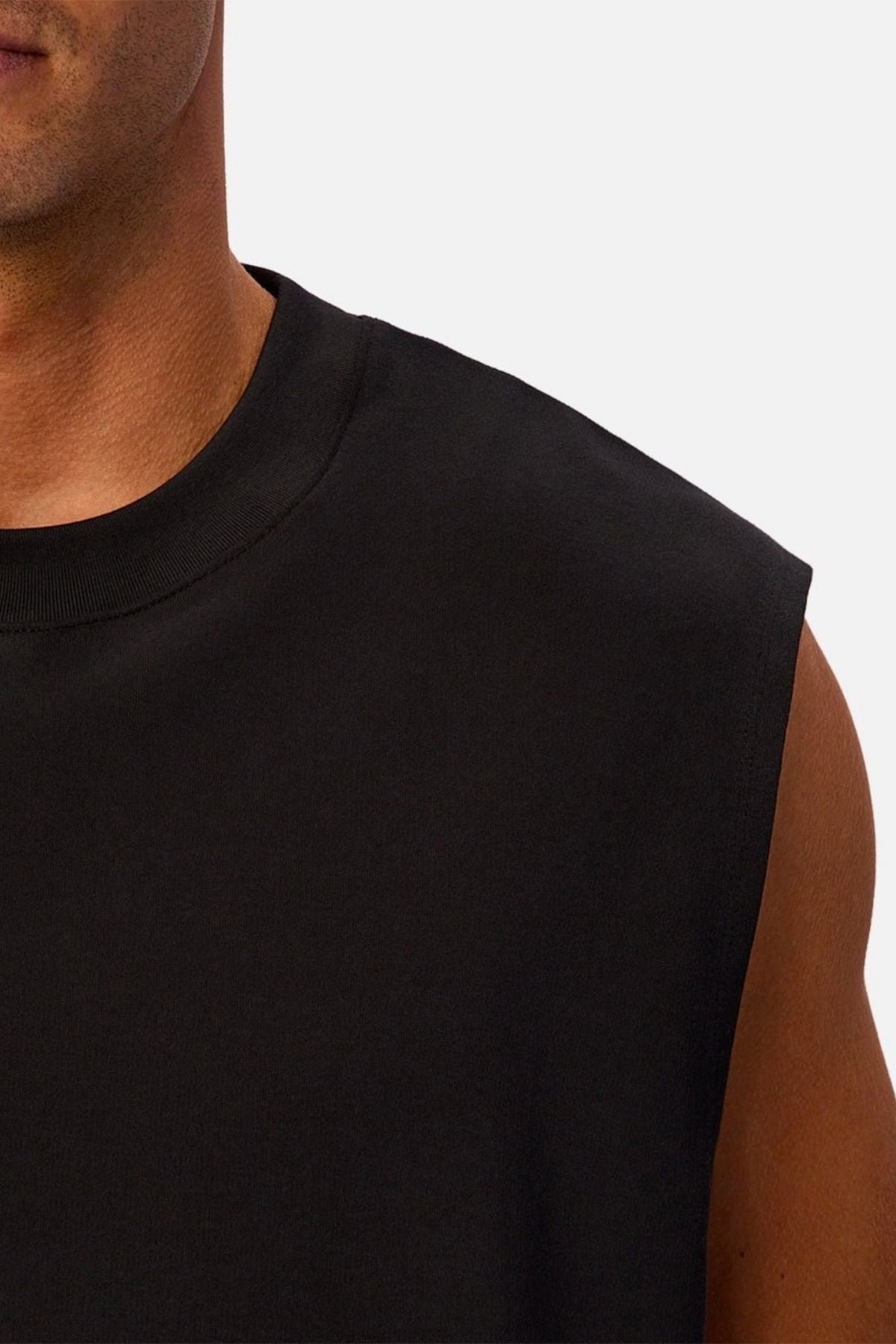 A close-up of a person wearing the Industrie The Tech Port Sleeveless Tee in black against a plain light background, highlighting part of their face, neck, shoulder, and upper chest.