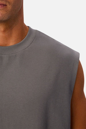 A close-up of a person wearing the Industrie The Tech Port Sleeveless Tee in gray, highlighting part of their neck, shoulder, and upper arm against a plain background. The relaxed fit and technical fabric emphasize comfort and modern style.