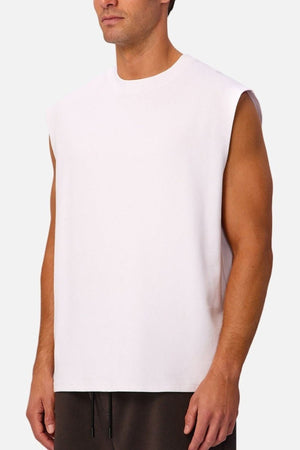 A man wearing the Industrie The Tech Port Sleeveless Tee and dark pants stands against a plain background, looking to the side.