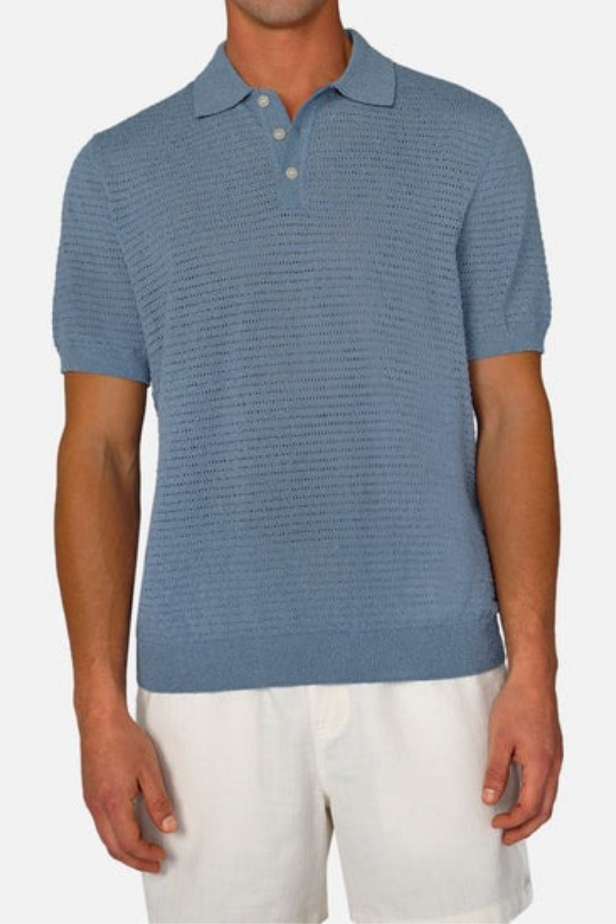 A man wearing a light blue Industrie The Terracina Polo and white shorts stands against a plain background. The polo is designed with a collar, three buttons, and a vertical ribbed texture. Made from lightweight material, this outfit exudes a casual and summer-appropriate look.