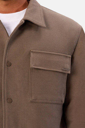 A close-up shows someone wearing the Industrie The Westport Jacket with flap press stud buttons over a white t-shirt, revealing only part of their neck and upper body.