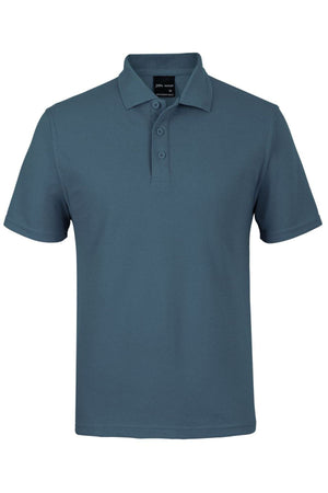 The JBs Short Sleeve Polo is a teal shirt with UPF protection, featuring short sleeves, a collar, and three buttons down the front. Displayed on a white background.