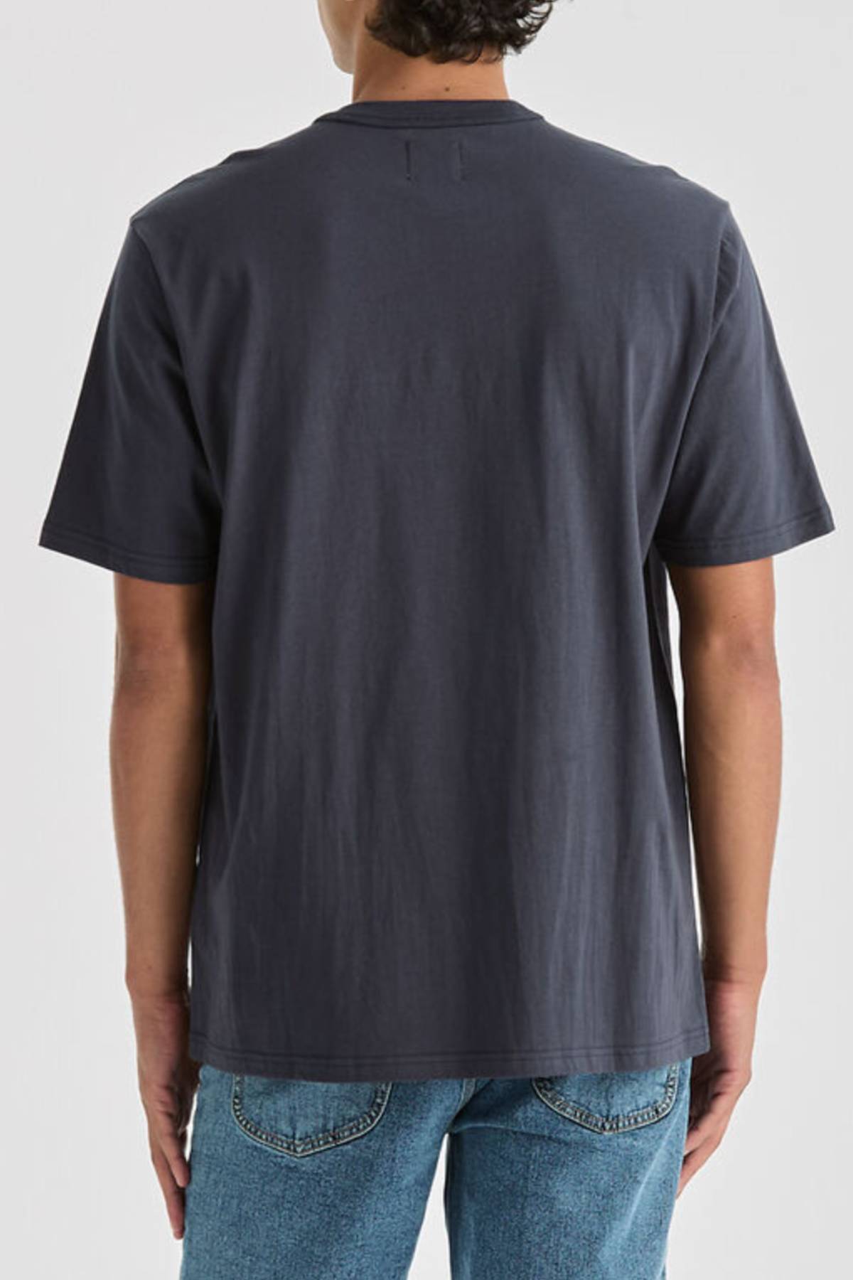 A person is shown from the back, standing against a light background, wearing a plain dark gray Lee Originals Relaxed Tee and blue jeans.