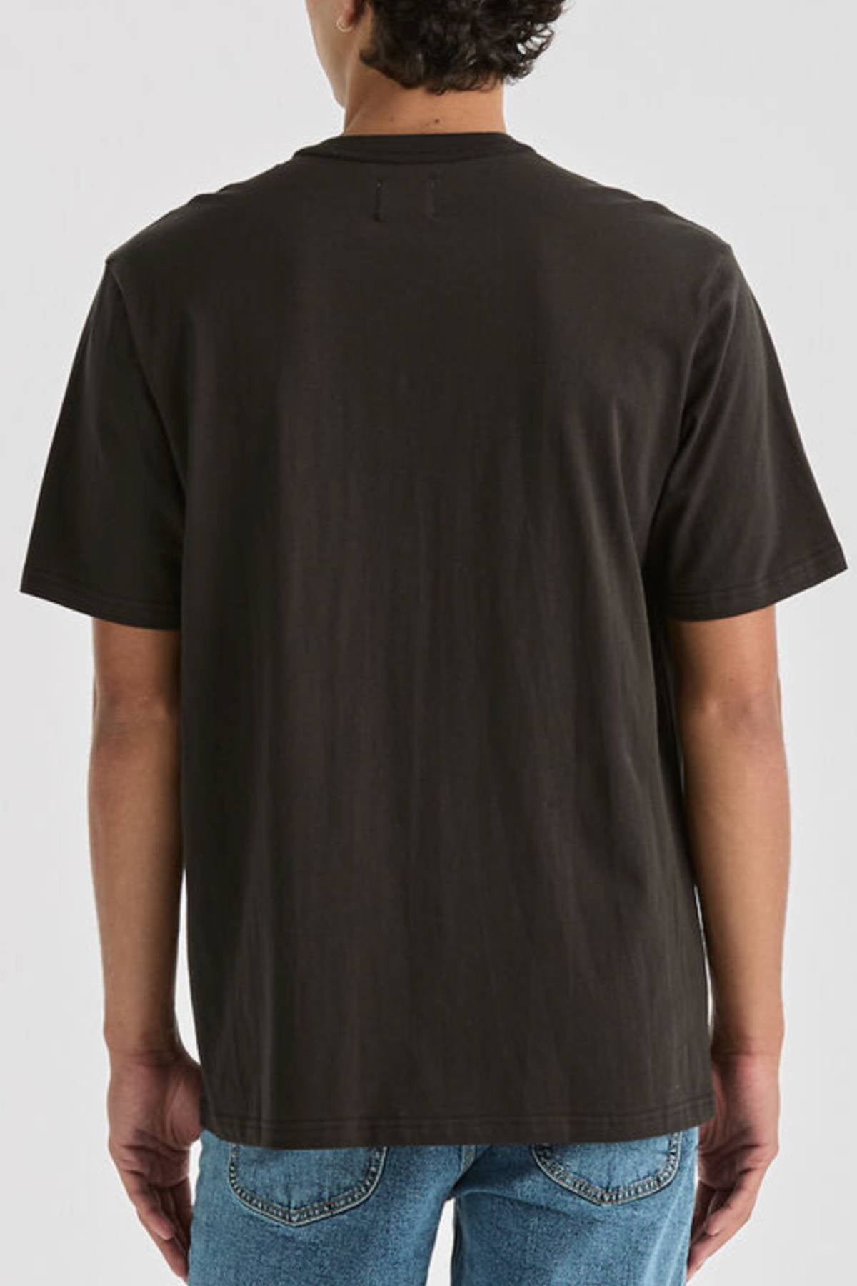 Someone in the Lee Originals Relaxed Tee, a plain black 100% cotton T-shirt, paired with blue jeans, stands facing away against a light gray background.