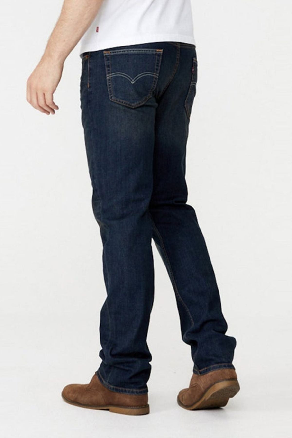 A person wearing Levis 514 Straight Jeans and brown shoes stands facing away, with only their lower body visible.