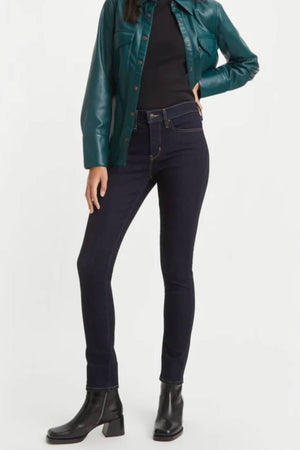 Wearing a green leather jacket, black top, Levis 311 Shaping Skinny Jean, and black ankle boots, a person stands with one hand on their hip against a plain background.