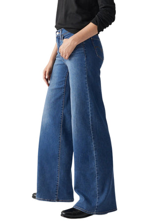 A person in a black long-sleeve top and Levis 318 Shaping Wide Leg Jean with black shoes, shown from the side on a white background.