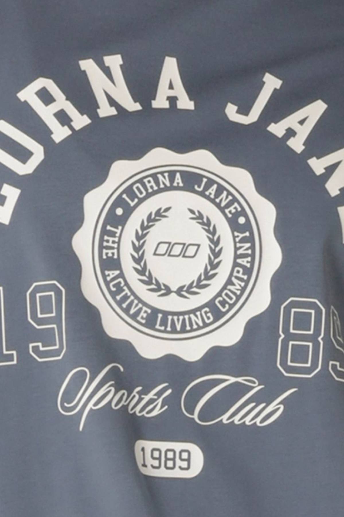 The Lorna Jane Active Living Relaxed T-Shirt features a limited edition circular logo with laurels, "The Active Living Company," 1989, and "Sports Club" in script above the year.