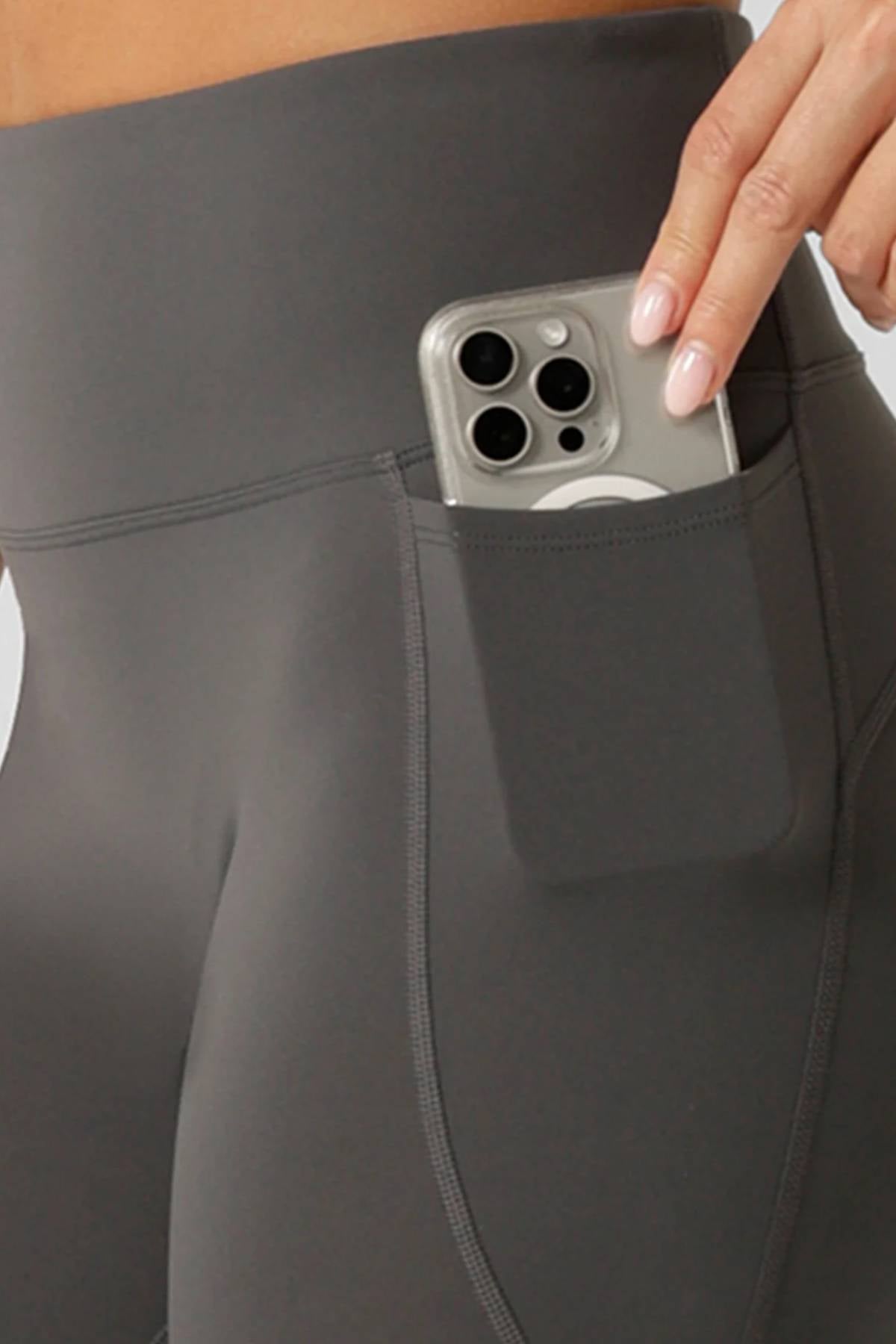 Someone, visible only from the waist down, slips a smartphone into a side pocket of Lorna Jane Amy No Ride Phone Pocket Ankle Biter Leggings featuring Active Core Stability™.